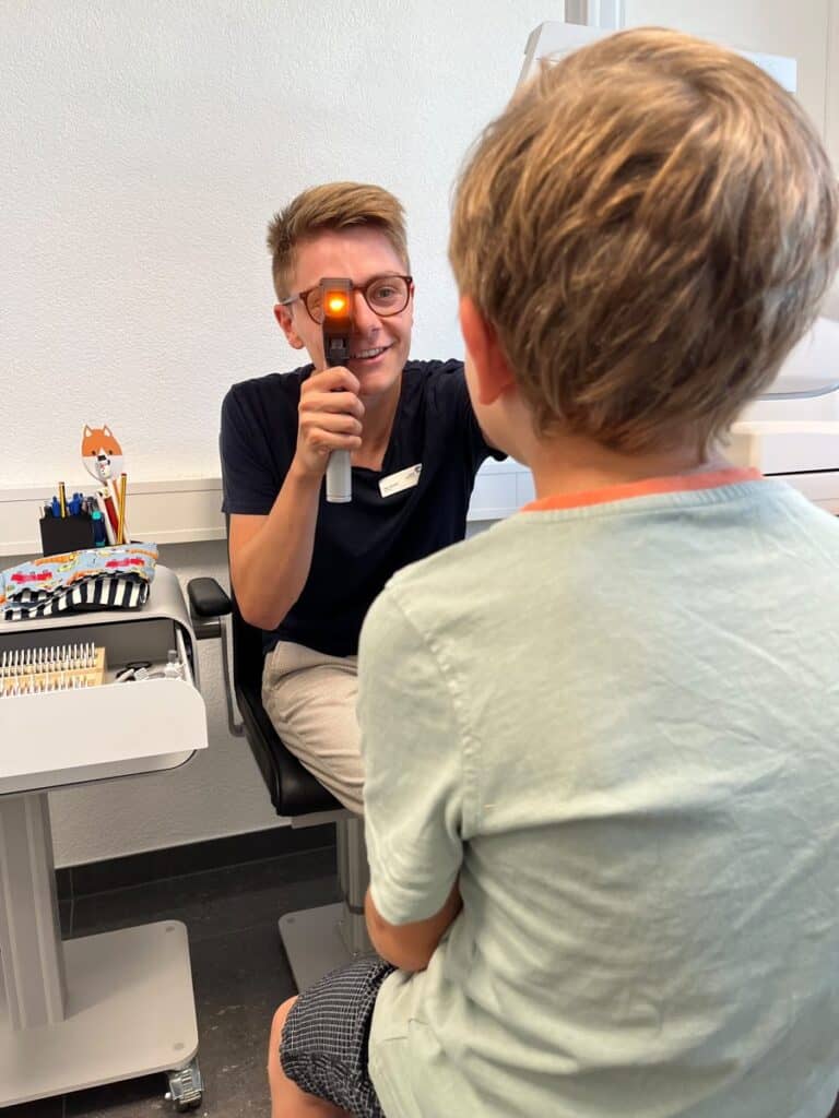 Kinderaugensprechstunde Augenzentrum Interlaken Orthoptist Marc Amacher untersucht die Augen eines Kindes im Augenzentrum Interlaken – Kinderaugensprechstunde
